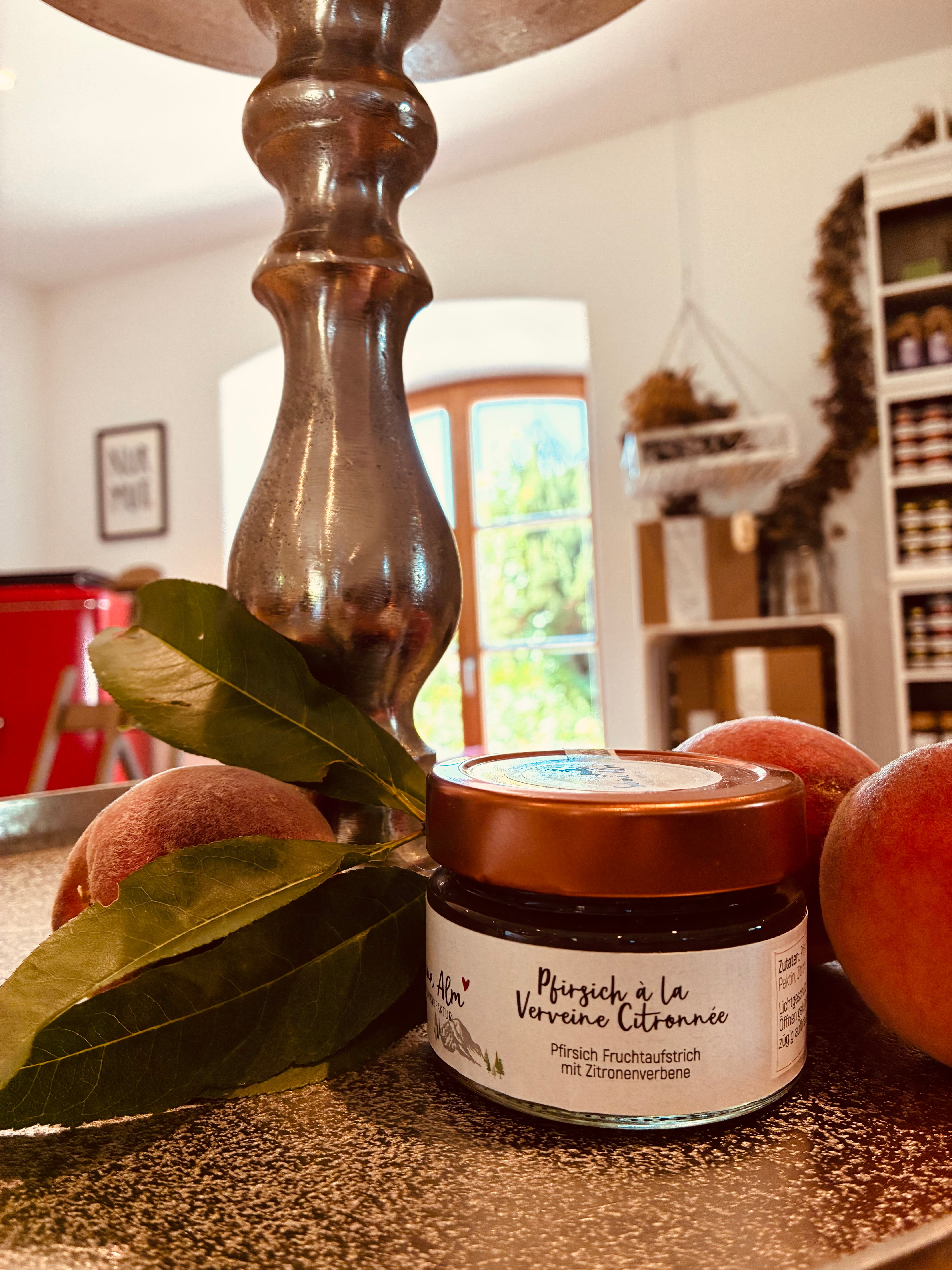 Pfirsich à la Verveine Citronnée – handgemachter Pfirsich-Fruchtaufstrich mit Zitronenverbene im Glas, dekoriert mit frischen Pfirsichen.